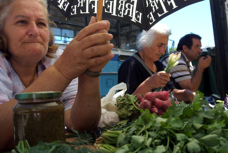 A street vendor holds an umbrella to avoid the sun in the northern port city of Thessaloniki, Greece, on Tuesday, June 19, 2012. European leaders are locked in a fierce debate over how to solve the debt crisis that is killing off growth on the continent, including whether to ease up on the terms of Greece's bailout deal.(AP Photo/Nikolas Giakoumidis )