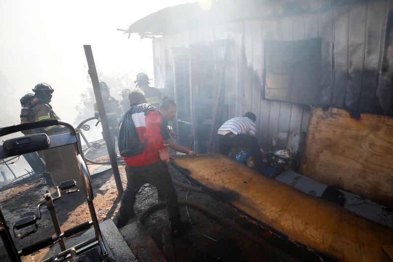 People help firefighters as they work to extinguish a fire in Valparaiso