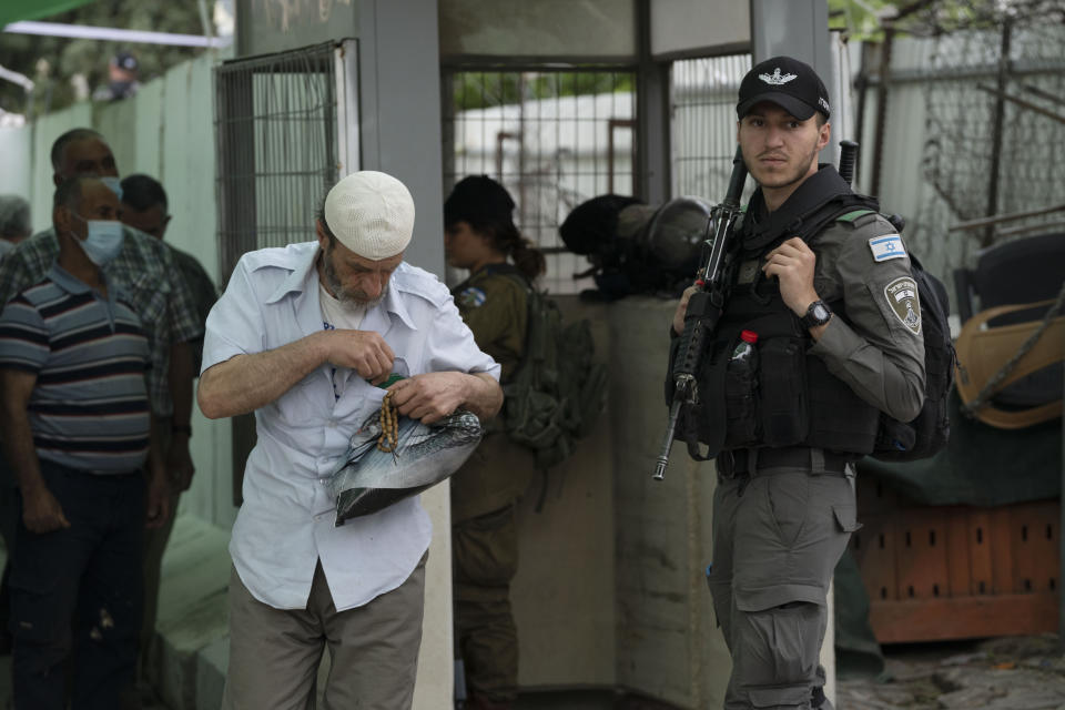 FILE - An Israeli Border Police officer secures a checkpoint from the West Bank town of Bethlehem into Jerusalem as a Palestinian man puts away his ID card while crossing for prayers during the Muslim holy month of Ramadan at the Al Aqsa mosque compound in Jerusalem's Old City, Friday, April 8, 2022. The apparent comeback of former Prime Minister Benjamin Netanyahu and the dramatic rise of his far-right and ultra-Orthodox allies in Israel's general election this week have prompted little more than shrugs from many Palestinians. (AP Photo/Maya Alleruzzo, File)