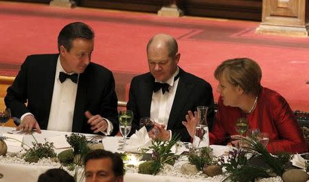 German Chancellor Angela Merkel (R) gestures as she talks to Britain's Prime Minister David Cameron (L) and Hamburg's Mayor Olaf Scholz (C) after Cameron's speech during the traditional historic banquet "Matthiae-Mahlzeit" (St. Matthew's Day Banquet) at the town hall in Hamburg February 12, 2016. REUTERS/Morris Mac Matzen