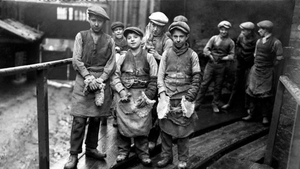 Group of children wearing aprons outside a factory in Swansea