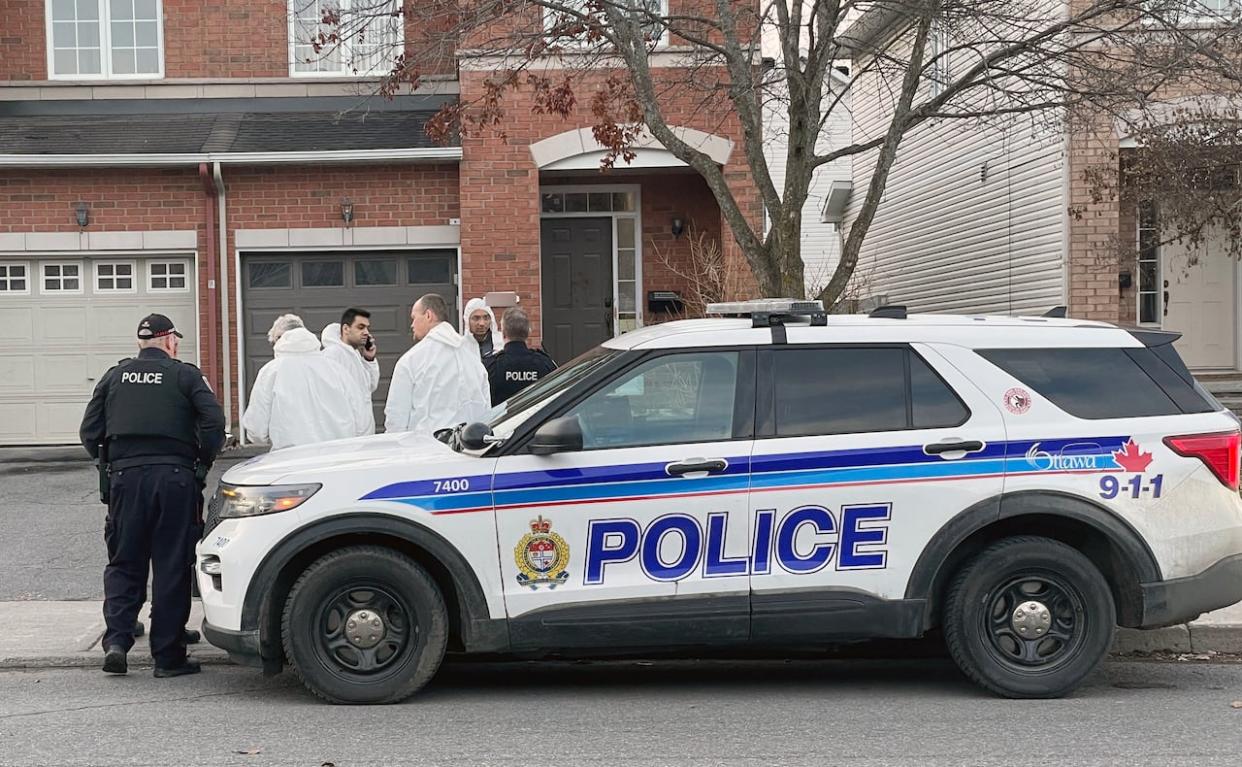 Forensic investigators and other Ottawa police officers gather outside a townhouse in the suburb of Barrhaven on March 7, 2024, where six people were killed.  (Radio-Canada - image credit)