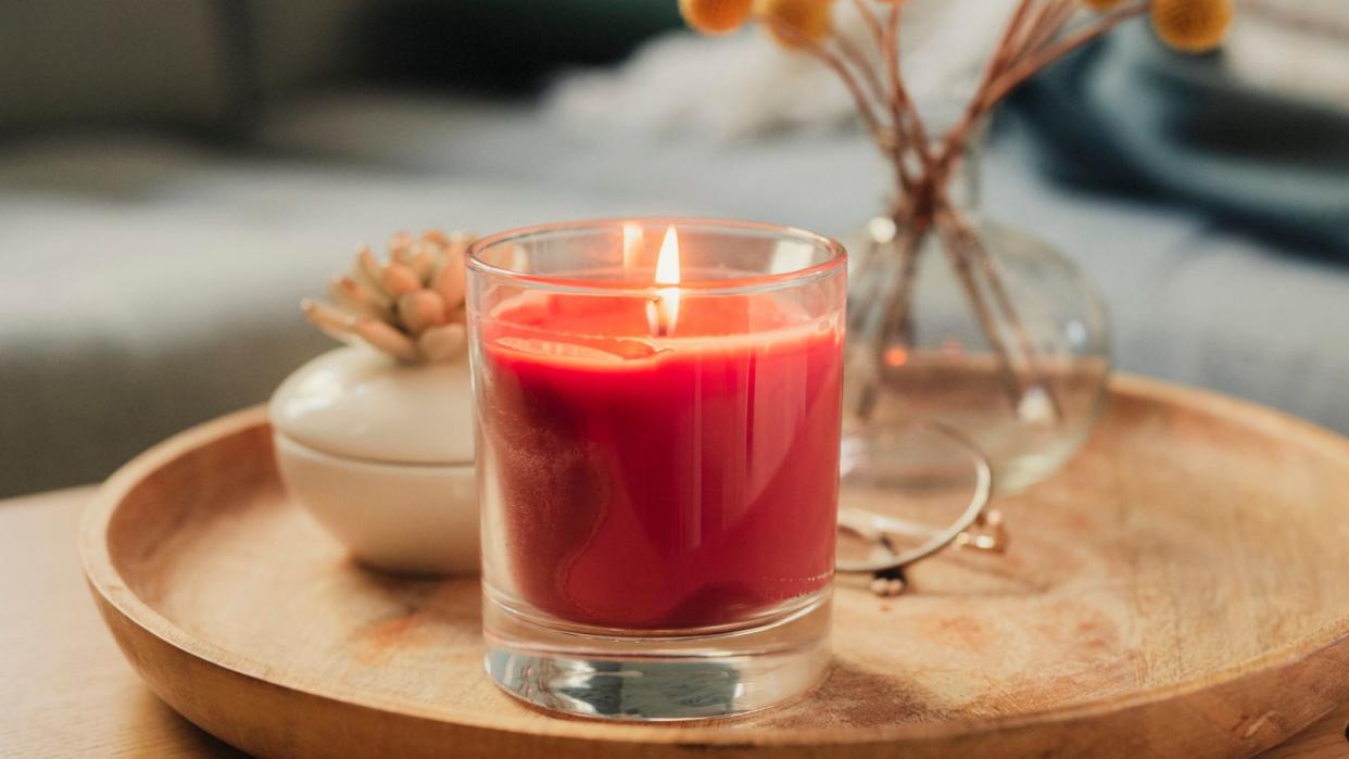  Are scented candles toxic? An example of a scented candle, a red candle on a wooden coffee table. 