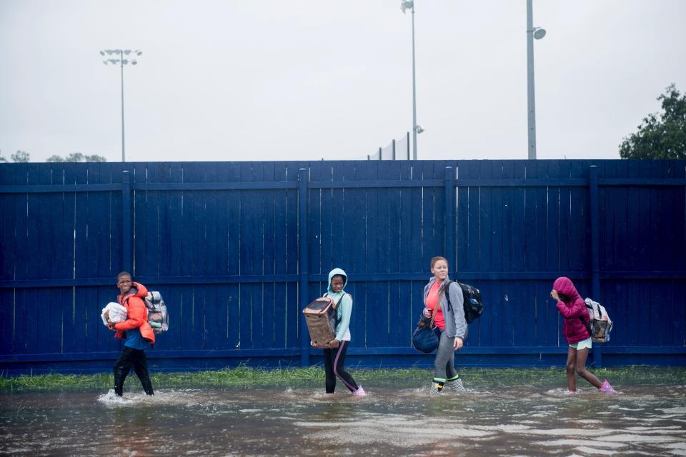 People walk to a Harris County Sheriff's Office air boat while escaping a flooded neighborhood in Houston.