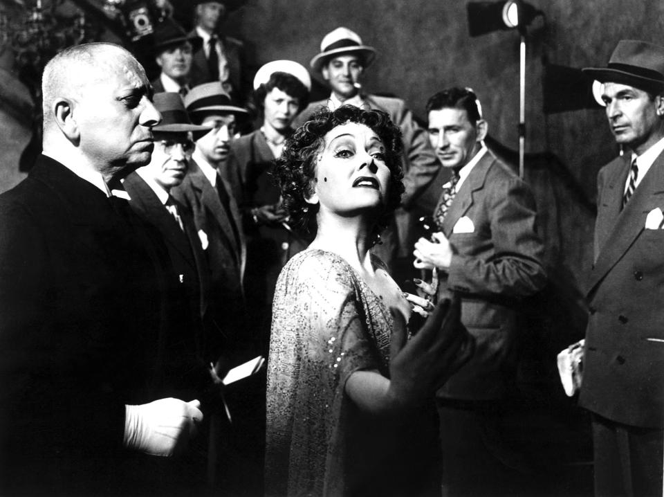 Gloria Swanson descends a staircase full of people