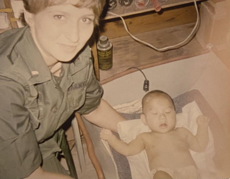 Anna Kathryn Tolbert leans over a baby with a leg wound.