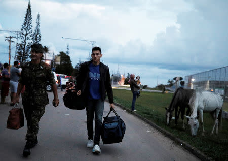 A Venezuelan man is helped by Brazilian Colonel Zannata across the border after he shows his onwards airline ticket for Foz do Iguacu at the Pacaraima border control, Roraima state, Brazil August 19, 2018. REUTERS/Nacho Doce