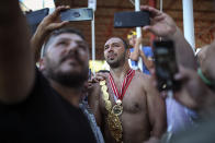 Wrestler Ali Gurbuz poses for pictures with fans after winning the final to gain the sport's golden belt in the 660th instalment of the annual Historic Kirkpinar Oil Wrestling championship, in Edirne, northwestern Turkey, Sunday, July 11, 2021.Thousands of Turkish wrestling fans flocked to the country's Greek border province to watch the championship of the sport that dates to the 14th century, after last year's contest was cancelled due to the coronavirus pandemic. The festival, one of the world's oldest wrestling events, was listed as an intangible cultural heritage event by UNESCO in 2010. (AP Photo/Emrah Gurel)