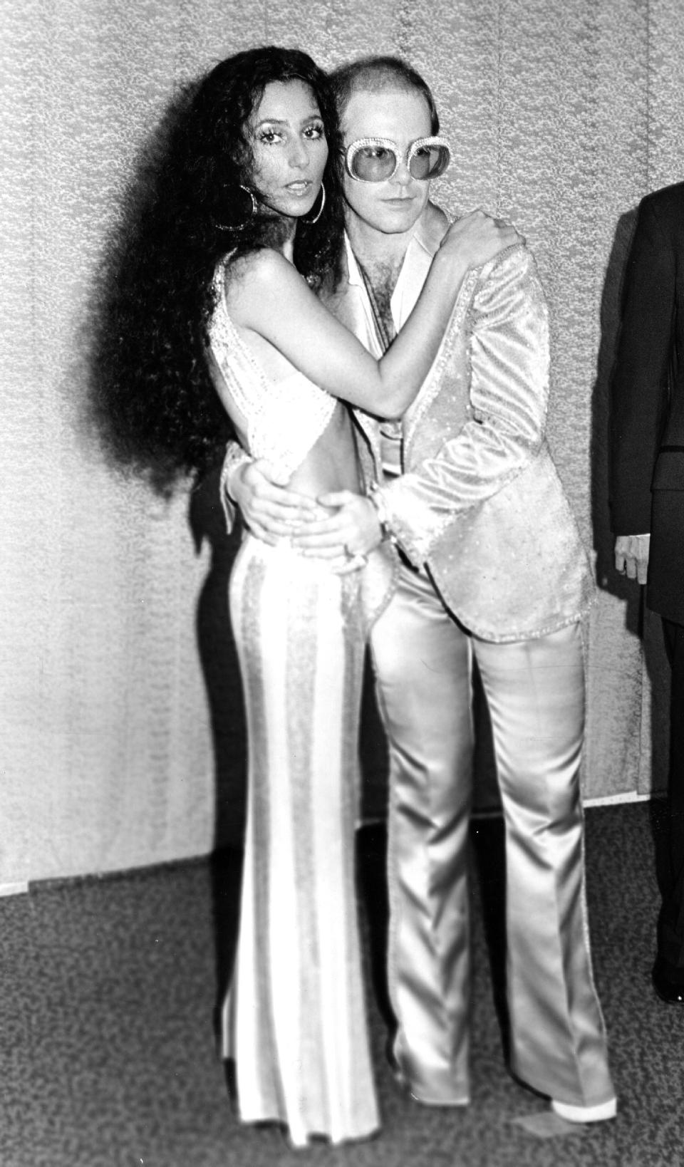 Cher and Elton John pose for a portrait backstage at an awards show.