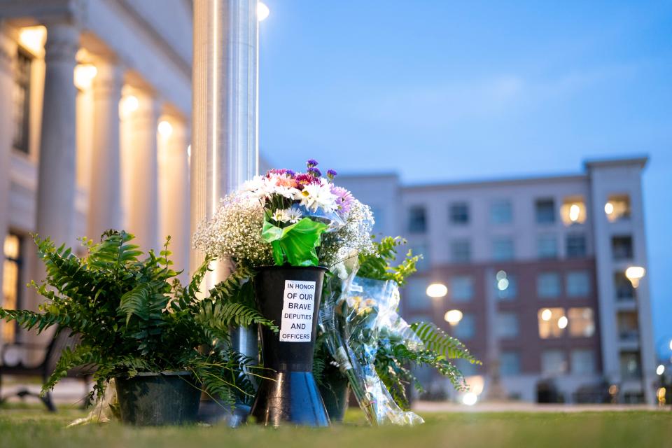 Flowers in memory of fallen law enforcement officers accumulate at the base of a flag pole outside the Federal Courthouse on April 30, 2024 in Charlotte, North Carolina. Four members of law enforcement were shot and killed the previous day while serving a warrant at a residence in Charlotte.