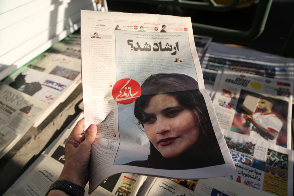 A person holds up an Iranian newspaper with a cover story about the death of Mahsa Amini.