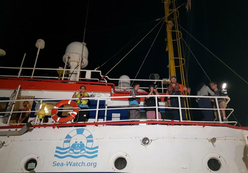 Captain Carola Rackete, left, watches as the Dutch-flagged Sea-Watch 3 ship docks at Lampedusa island's harbor, Italy, early Saturday, June 29, 2019. Forty migrants have disembarked on a tiny Italian island after the captain of the German aid ship which rescued them docked without permission. Sea-Watch 3 rammed an Italian border police motorboat as it steered toward the pier on Lampedusa. Italian Interior Minister branded the captain, who was taken into custody, as an "outlaw" who put the lives of the police at risk. (Elio Desiderio/ANSA via AP)