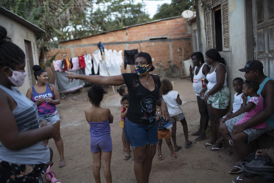 Residents gather as donated food, kits of cleaning products and protective face masks are distributed amid the new coronavirus pandemic at the Maria Joaquina "Quilombo" in Cabo Frio, on the outskirts of Rio de Janeiro, Brazil, Sunday, July 12, 2020. "Quilombo" residents are accustomed to communal life, but the pandemic has broken traditional bonds by forcing people to wear masks and quarantine in their own homes. (AP Photo/Silvia Izquierdo)