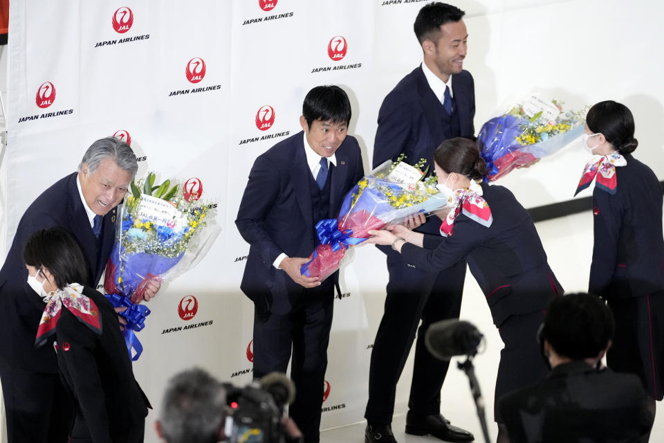 Japan's head coach Hajime Moriyasu, center and captain Maya Yoshida, center right, receive flowers as supporters welcome home Japanese national soccer team from the World Cup in Qatar, at Narita International Airport in Narita, east of Tokyo, Wednesday, Dec. 7, 2022.(AP Photo/Shuji Kajiyama)