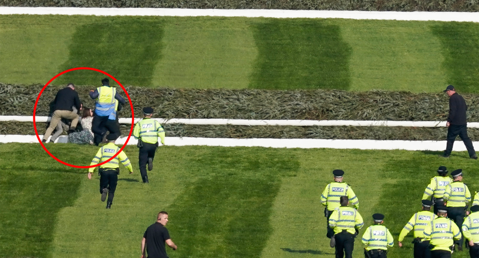 Police run towards protesters on the Grand National track.