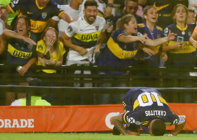 Carlos Tevez se hinca tras anotar el gol del título mientras los aficionados de Boca Juniors celebran