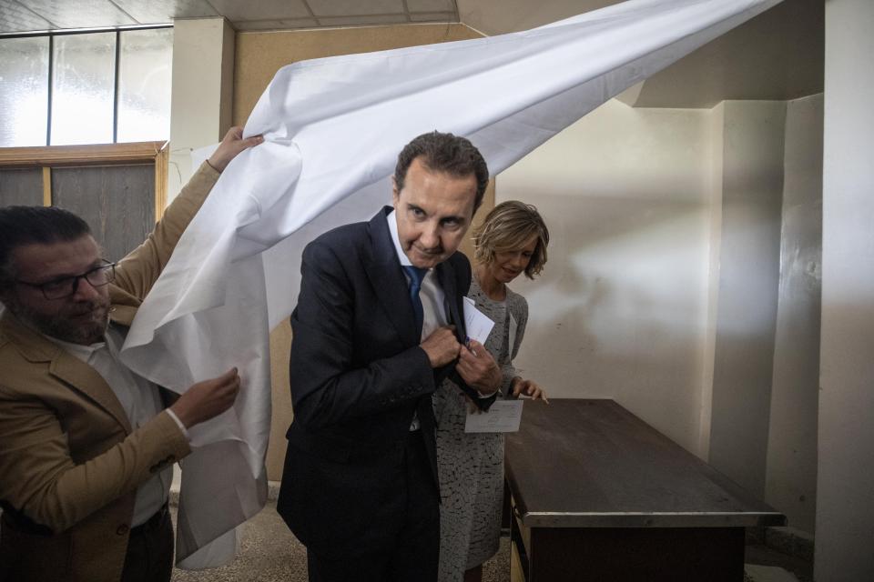 Syrian President Bashar Assad and his wife Asma prepare to vote at a polling station during the Presidential elections in the town of Douma, in the eastern Ghouta region, near the Syrian capital Damascus, Syria, Wednesday, May 26, 2021. Syrians headed to polling stations early Wednesday to vote in the second presidential elections since the deadly conflict began in the Arab country. (AP Photo/Hassan Ammar)