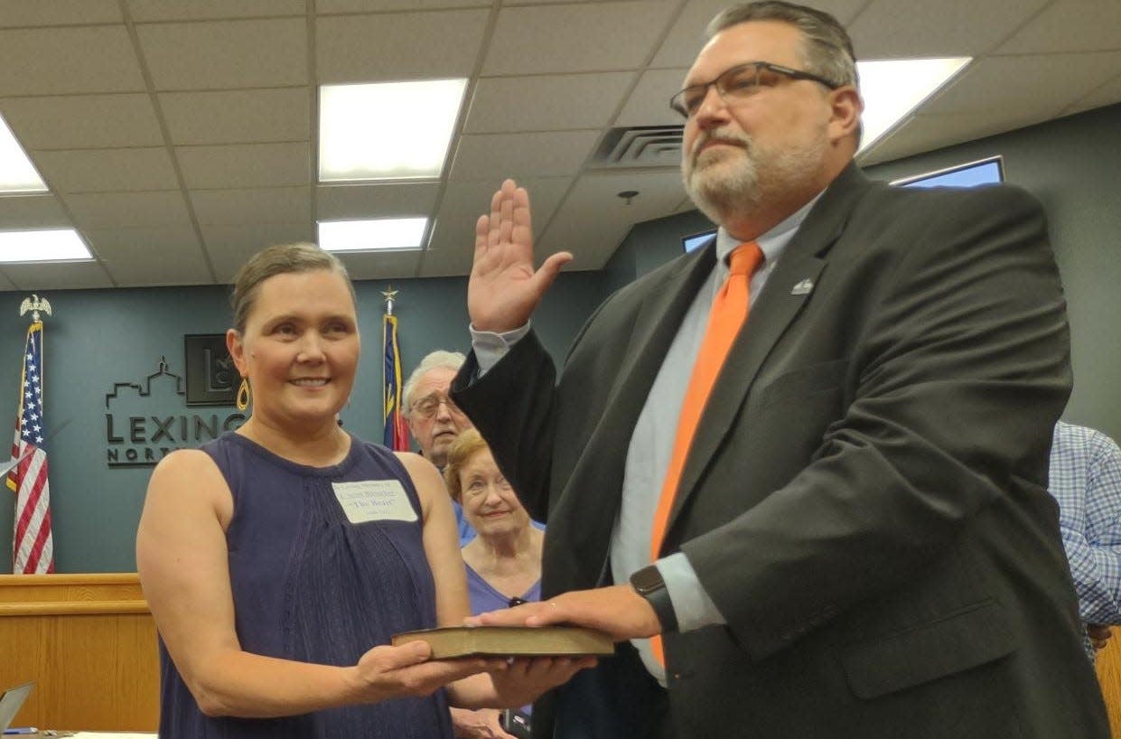 Jason Hayes is sworn in at the new Mayor of Lexington at the July 11 city council meeting while his wife Anna holds the bible.