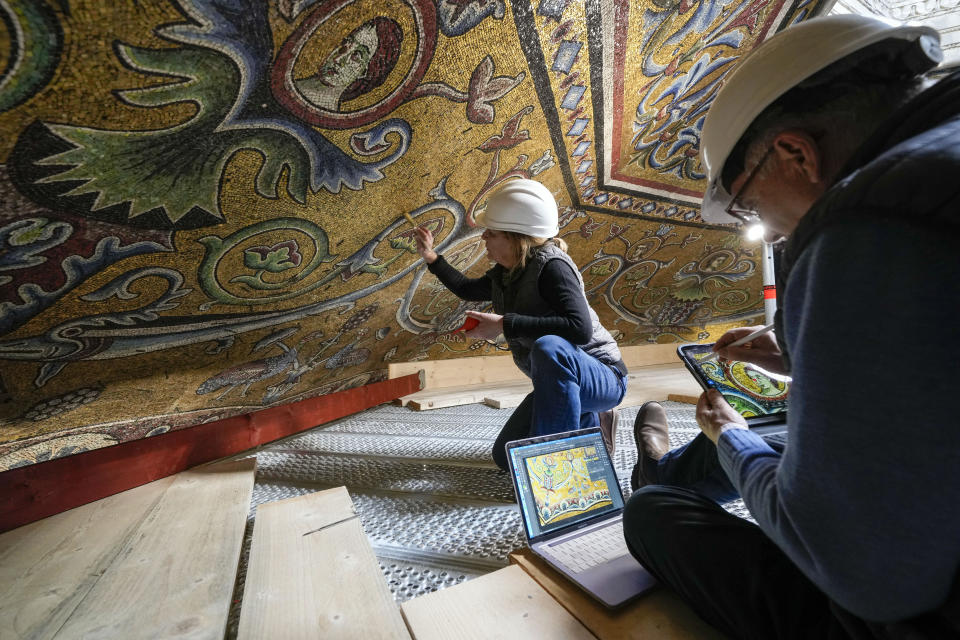 Los restauradores Chiara Zizola, derecha, y Roberto Nardi trabajan en la restauración de los mosaicos que adornan la cúpula de un monumento emblemático de Florencia, el Bautisterio de San Juan,, 7 de febrero de 2023. Un enorme andamio que se alza desde el centro de la iglesia estará abierto al público para que pueda ver de cerca los mosaicos. (AP Foto/Andrew Medichini)