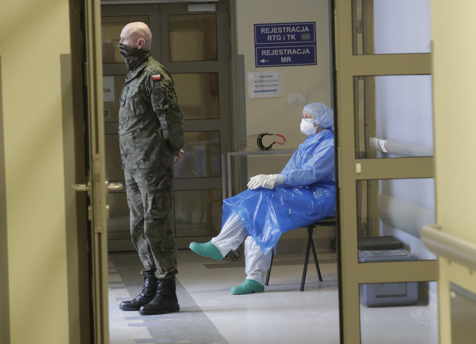 A Polish soldier and a nurse wait in a hallway in a hospital in Krakow, Poland, Friday Feb. 12, 2021, during the vaccination of teachers against the coronavirus with the AstraZeneca vaccine. As Poland began vaccinating teachers on Friday, many say they are unhappy that they are getting AstraZeneca vaccines against the coronavirus, rather than the Pfizer shots earmarked for health care workers and the elderly. Nearly a year into the pandemic, many Europeans and others globally are desperate to get vaccinated and return to normal life. But many don't want just any vaccine. (AP Photo/Czarek Sokolowski)
