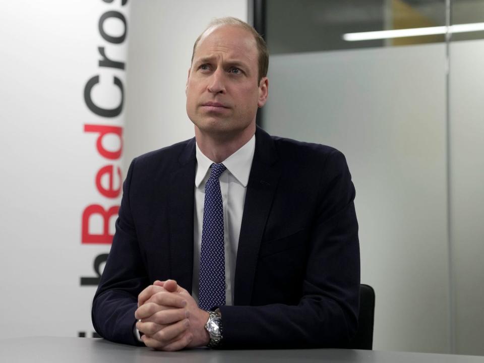 Prince William sits at a table with his hands clasped.