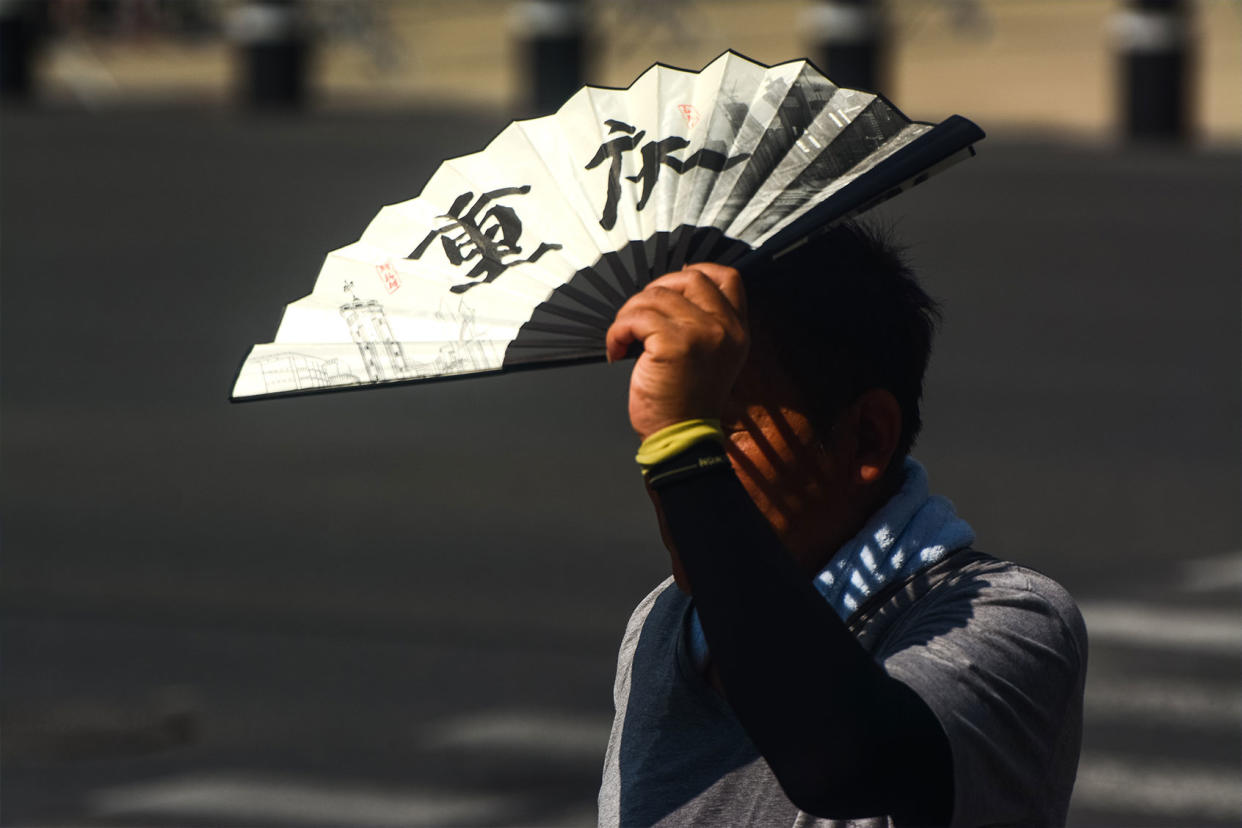 A man is seen blocking the sun with a fan at Shanghai, China, on July 6, 2023 as Shanghai issues an orange alert for the continuous heatwave.Ying Tang/NurPhoto via Getty Images