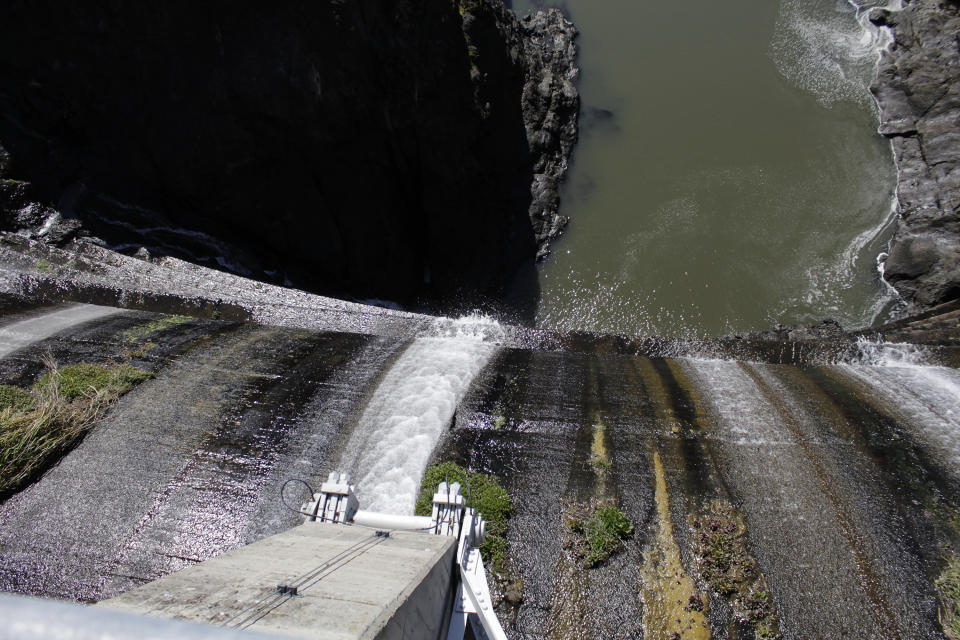 FILE - In this March 3, 2020 file photo, excess water spills over the top of a dam on the Lower Klamath River known as Copco 1 near Hornbrook, Calif. California Gov. Gavin Newsom has appealed directly to investor Warren Buffet to support demolishing four hydroelectric dams on a river along the Oregon-California border to save salmon populations that have dwindled to almost nothing. Newsom on Wednesday, July 28, 2020, wrote Buffet, urging him to back the Klamath River project, which would be the largest dam removal in U.S. history. (AP Photo/Gillian Flaccus, File)