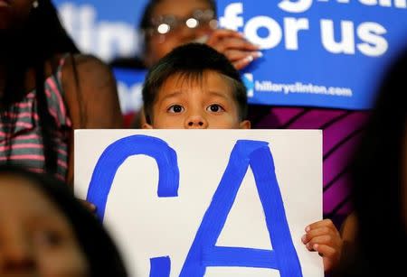 A young boy looks on as U.S. Democratic presidential candidate Hillary Clinton delivers a speech during a campaign stop in Fresno, California, United States June 4, 2016. REUTERS/Mike Blake
