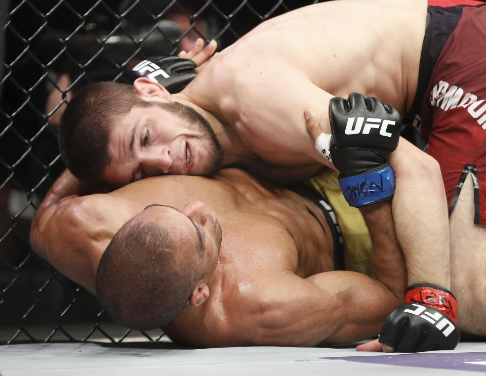 Khabib Nurmagomedov, top, fights Edson Barboza in a lightweight mixed martial arts bout at UFC 219, Saturday, Dec. 30, 2017, in Las Vegas. (AP Photo/John Locher)