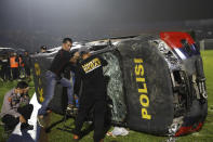 Officers examine a damaged police vehicle following a clash between supporters of two Indonesian soccer teams at Kanjuruhan Stadium in Malang, East Java, Indonesia, Saturday, Oct. 1, 2022. Panic following police actions left over 100 dead, mostly trampled to death, police said Sunday. (AP Photo/Yudha Prabowo)