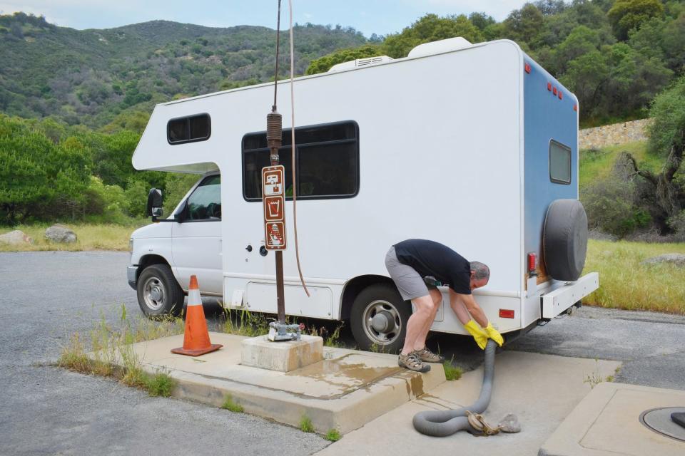 Make sure the dump valves are closed before you open the storage compartment on the side of the vehicle to remove the cap and connect the sewer hose.