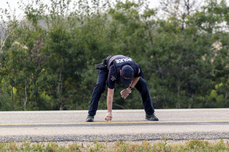 A Royal Canadian Mounted Police officer lays down a marker on a road outside Rosthern, Saskatchewan on Wednesday, Sept. 7, 2022. Canadian police arrested Myles Sanderson, the second suspect in the stabbing deaths of multiple people in Saskatchewan, after a three-day manhunt that also yielded the body of his brother fellow suspect, Damien Sanderson.(Heywood Yu/The Canadian Press via AP)