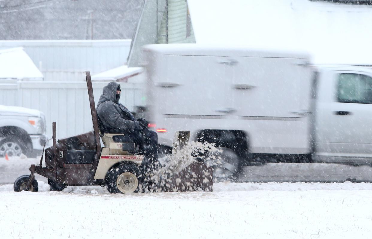 A worker clears slushy snow from the sidewalk near Twin Branch Elementary School along Lincoln Way East in Mishawaka on Tuesday.