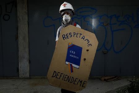 A demonstrator holding a rudimentary shield that depicts the Venezuelan Constitution and reads "Respect me" and "Defend me", poses for a picture before a rally against Venezuelan President Nicolas Maduro's government in Caracas, Venezuela, June 17, 2017. REUTERS/Carlos Garcia Rawlins