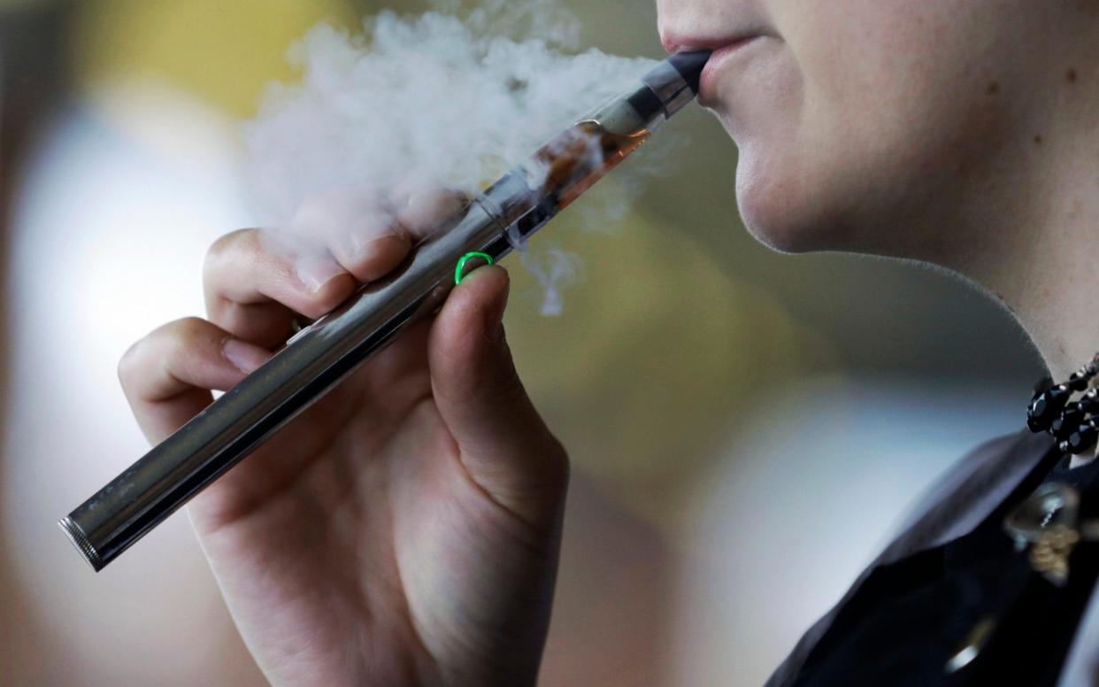 In this Oct. 4, 2019, file photo, a woman using an electronic cigarette exhales - Tony Dejak/AP