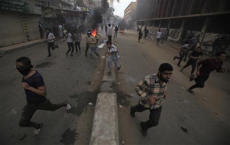 Supporters of the Muslim Brotherhood and ousted Egyptian President Mohamed Mursi flee and run near burning tyres, from tear gas fired by riot police and army, during clashes at El-Talbyia near Giza square, south of Cairo, November 29, 2013. REUTERS/Amr Abdallah Dalsh