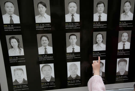 A girl reads the dates on a sign with portraits of staff members who died in the 2008 Sichuan earthquake, at the site of a branch of Agricultural Bank of China, in the city of Beichuan, Sichuan province, China, April 6, 2018. REUTERS/Jason Lee