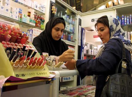 An Iranian woman tests the colours of make-up at an upscale shop in north Tehran in this November 8, 2003 file photo. REUTERS/Morteza Nikoubazl/Files