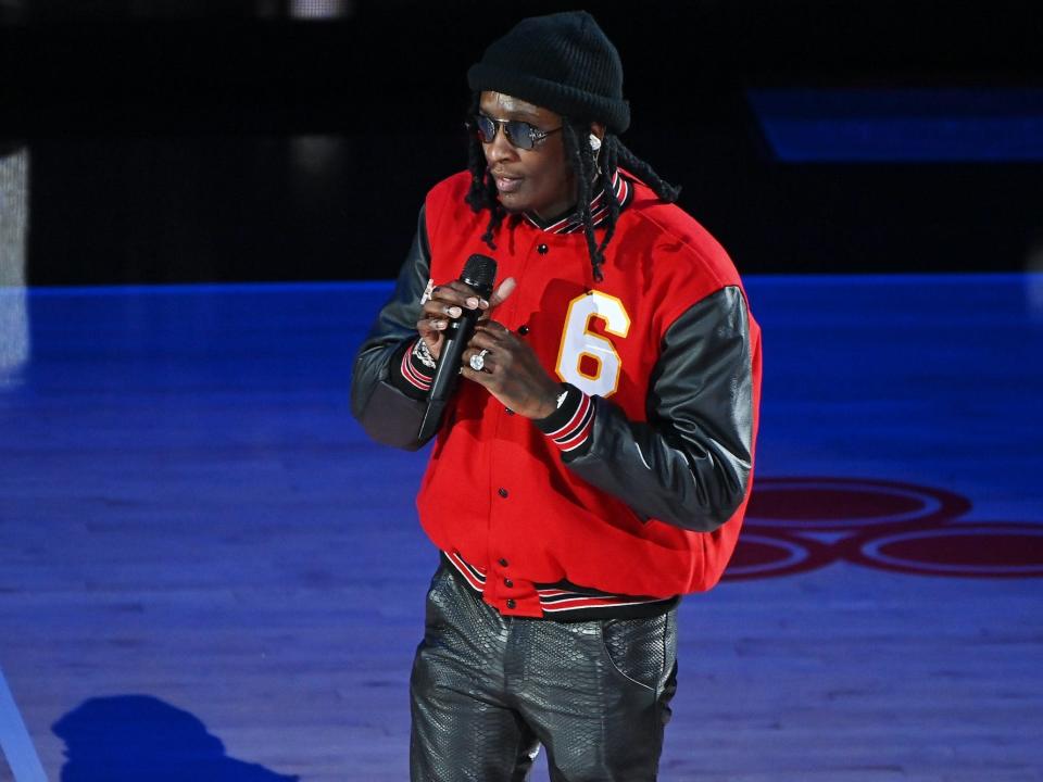 Young Thug with a microphone wearing a red jacket