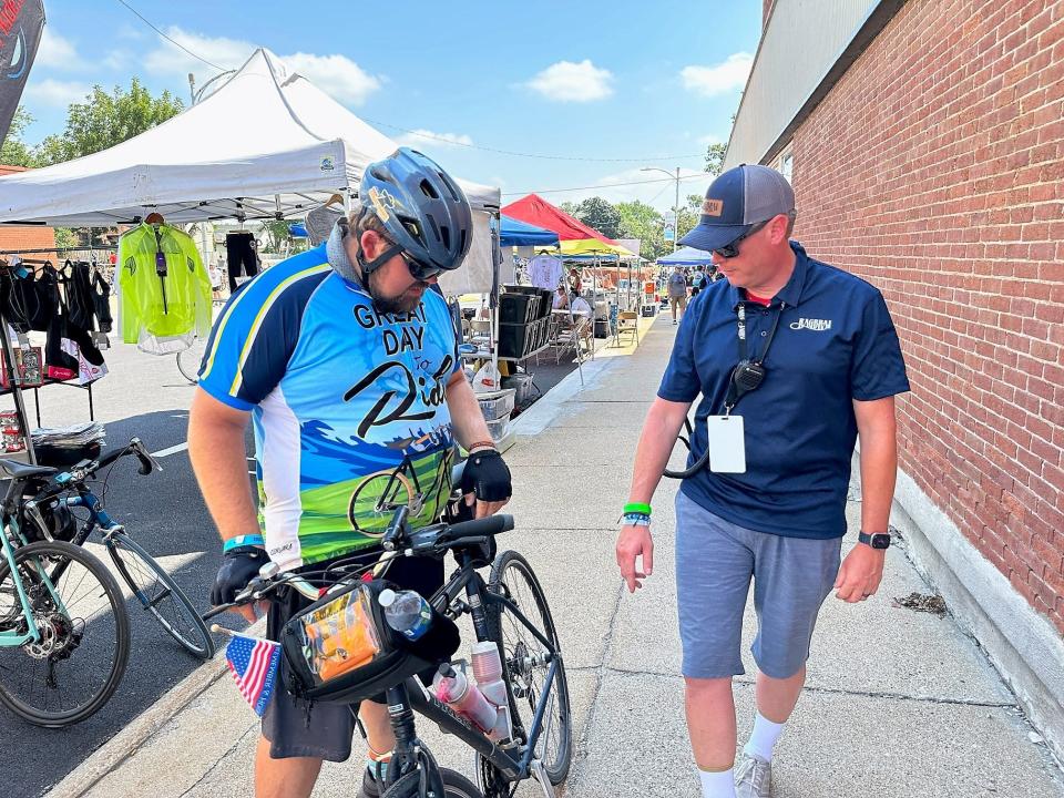 RAGBRAI ride director Matt Phippen, right, checks out the water bottles on a rider's bicycle in Madrid.