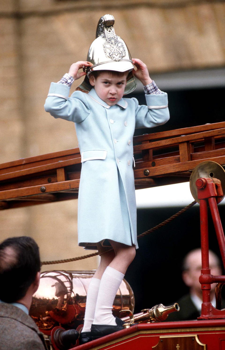 SANDRINGHAM, UNITED KINGDOM - JANUARY 03:  Prince William Trying On A Fireman's Helmet During A Photocall Held At The Sandringham Museum Of Royal Vehicles And Cars.during The Christmas Holidays At Sandringham. His Coat Is By Fashion Designer Catherine Walker.  (Photo by Tim Graham Photo Library via Getty Images)