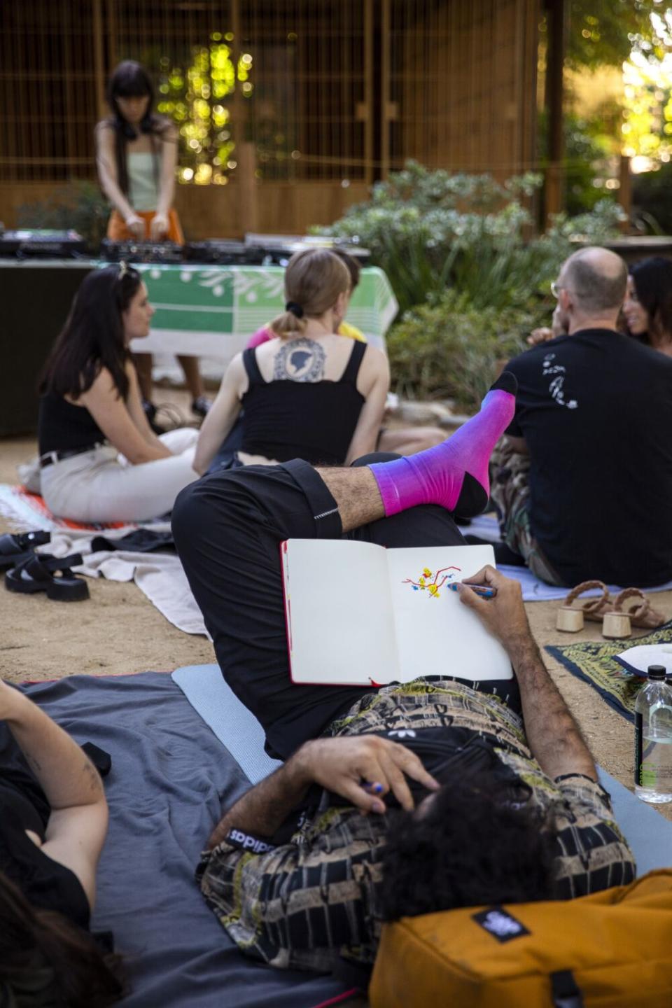 People chat, read, relax, draw and eat together as they enjoy music at a Floating event