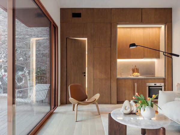 Wood paneling acts as an accent wall for the kitchenette, and as a unifying material for closed storage.