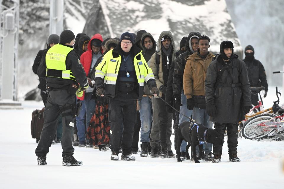 Finnish Border Guards escort migrants at the international border crossing between Finland and Russia, in Salla, Finland, Thursday, Nov. 23, 2023. (Jussi Nukari/Lehtikuva via AP)