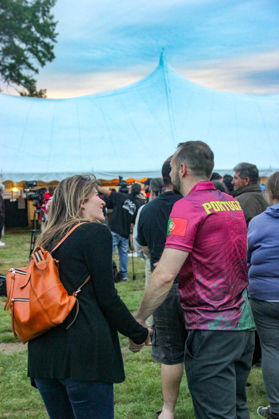 A couple waits for food outside the tent at the Great Feast of the Holy Ghost of New England on Thursday, Aug. 24, in Fall River.