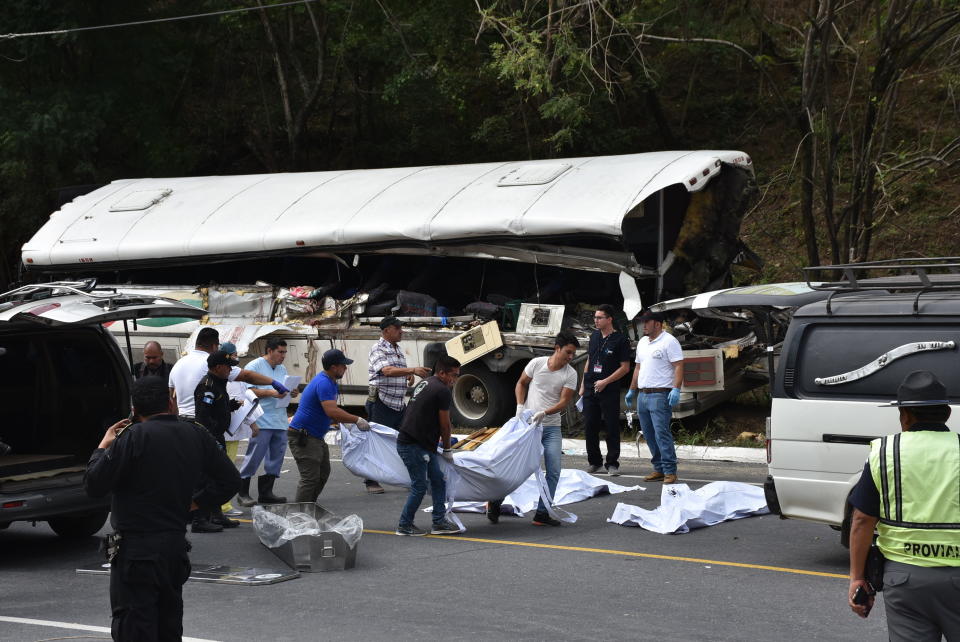 Rescue workers carry body bags with the remains of passengers after a deadly bus accident in Gualan, Guatemala, Saturday, Dec. 21, 2019. The accident killed at least 21 people and left a dozen wounded, according to the national disaster agency. (AP Photo/Carlos Cruz)
