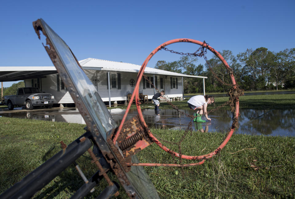 Grace Belaire, 7, and her brother, Mason, 5, look for worms and tadpoles in their driveway after Hurricane Delta pushed water around their home in southwest Louisiana on Saturday, Oct. 10, 2020. (Chris Granger/The Advocate via AP)