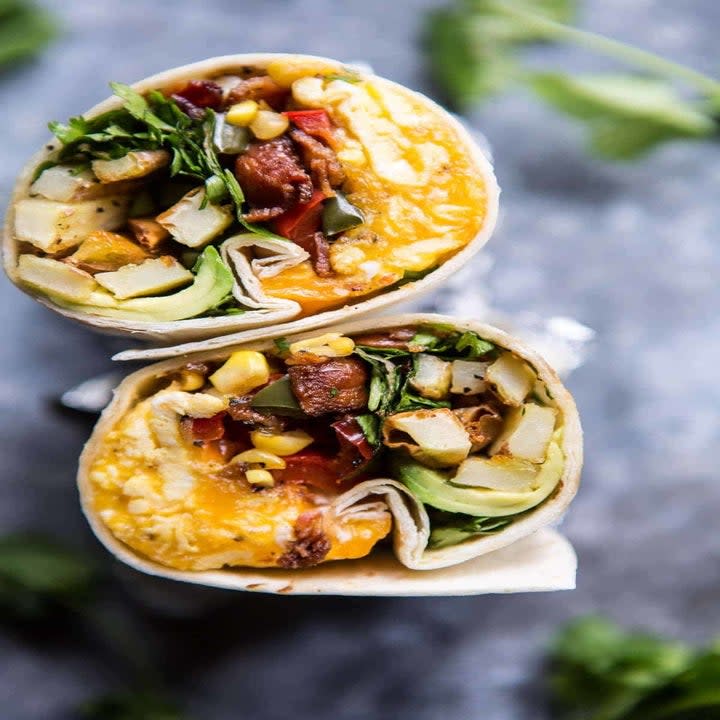 A breakfast burrito with avocado, bacon, and potatoes.