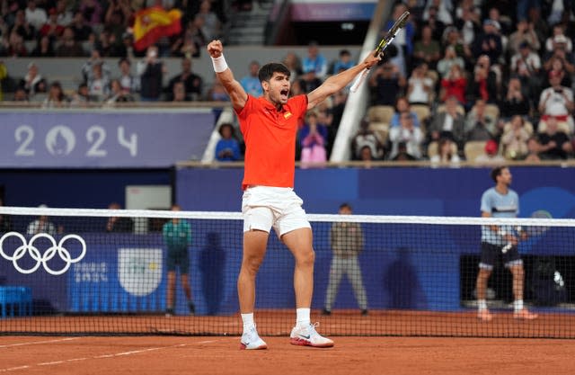 Carlos Alcaraz holds his arms aloft