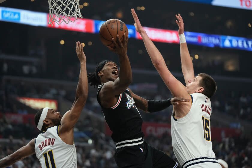 Los Angeles Clippers guard Terance Mann, center, shoots as Denver Nuggets forward Bruce Brown, left and center Nikola Jokic defend during the first half of an NBA basketball game Friday, Nov. 25, 2022, in Los Angeles. (AP Photo/Mark J. Terrill)